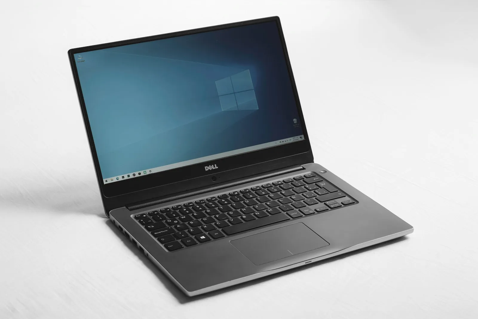 Portátil abierto con el escritorio de Windows en pantalla, sobre una superficie blanca